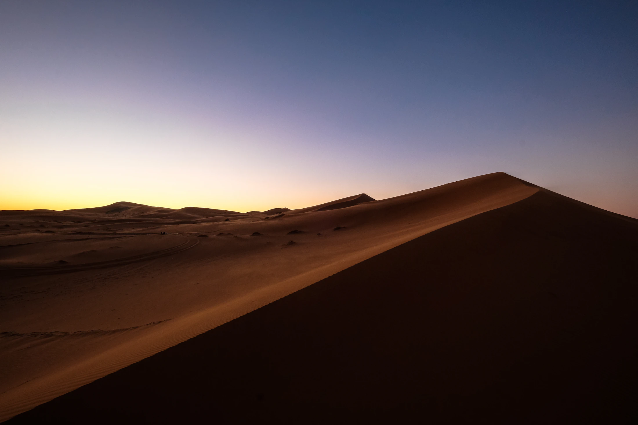 Dunas iluminadas pelo fim do dia, com uma linha de horizonte aberta